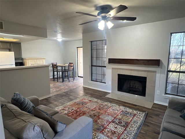 living room with dark hardwood / wood-style flooring, a tile fireplace, and ceiling fan