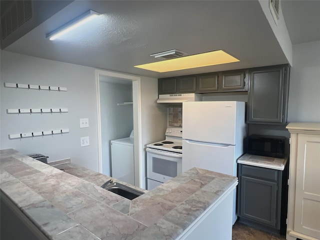 kitchen featuring gray cabinets, washer / dryer, sink, tile counters, and white appliances