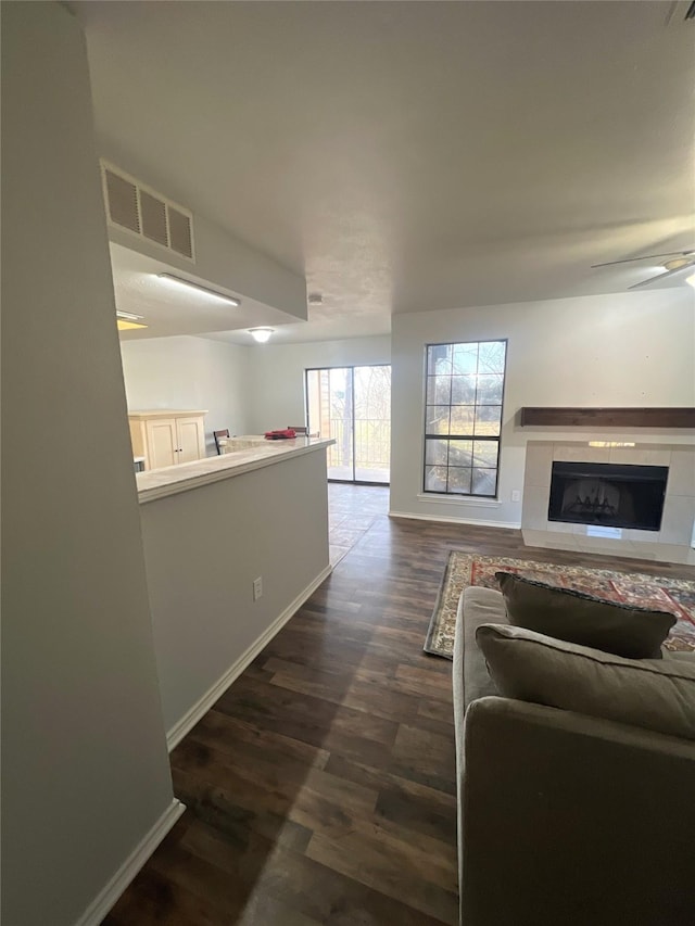 living room featuring a tiled fireplace and dark wood-type flooring