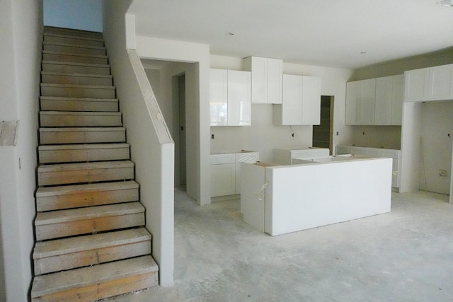 kitchen with a kitchen island with sink and white cabinets