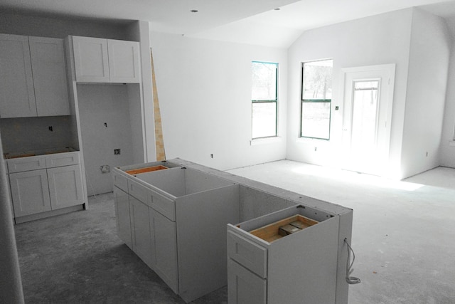 kitchen with white cabinetry, vaulted ceiling, and a center island