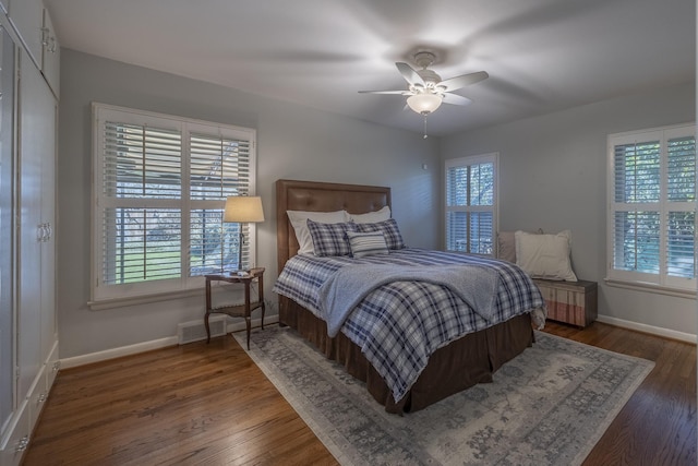 bedroom with multiple windows, dark wood-type flooring, and ceiling fan