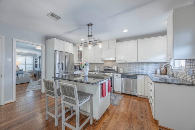 kitchen with white cabinetry, hanging light fixtures, stainless steel appliances, and a center island