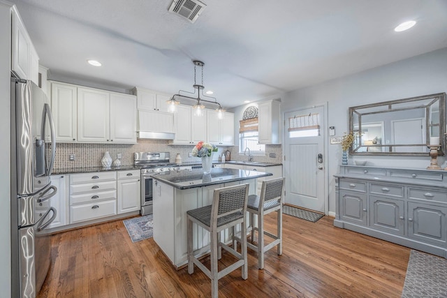 kitchen featuring decorative light fixtures, a center island, white cabinets, and appliances with stainless steel finishes