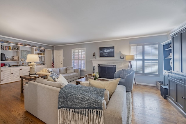 living room featuring crown molding, a fireplace, and light wood-type flooring