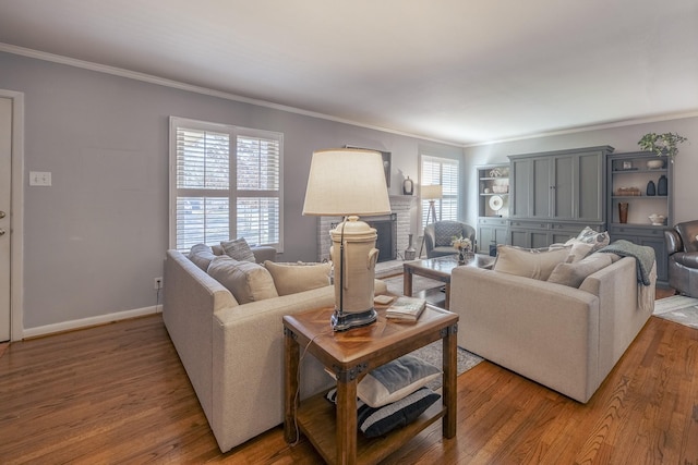 living room with ornamental molding, hardwood / wood-style floors, and a brick fireplace