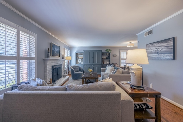 living room featuring hardwood / wood-style flooring, crown molding, and a brick fireplace