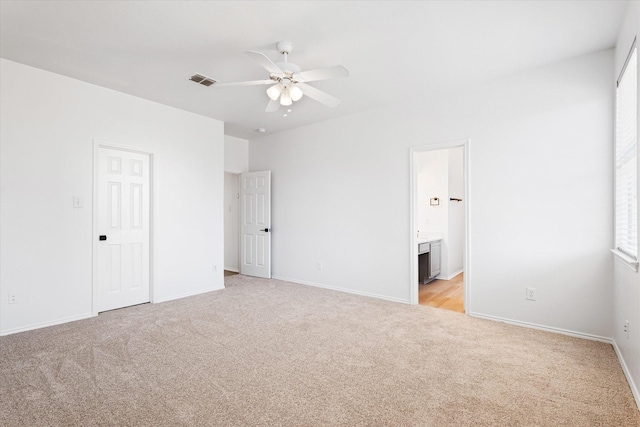 unfurnished bedroom with ensuite bathroom and light carpet