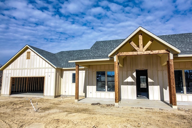 view of front of property featuring roof with shingles, board and batten siding, and a garage