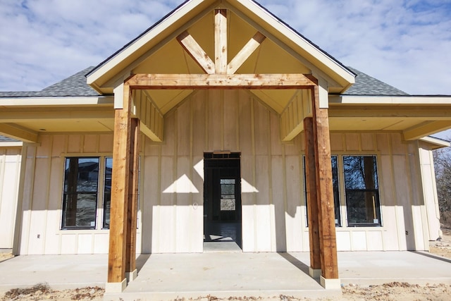 view of exterior entry with roof with shingles and board and batten siding
