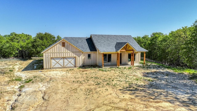 view of front of property with board and batten siding, covered porch, a shingled roof, driveway, and an attached garage