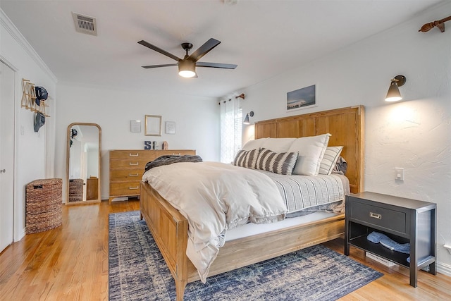 bedroom featuring crown molding, ceiling fan, and light wood-type flooring