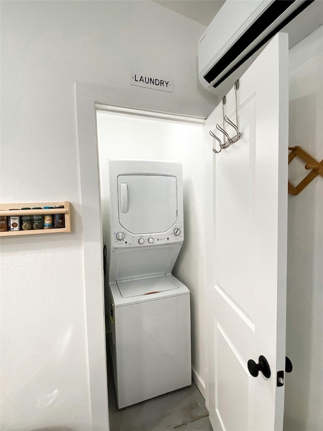 laundry area with a wall mounted air conditioner and stacked washer / dryer