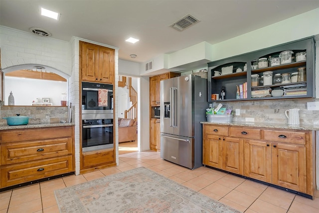 kitchen featuring stainless steel appliances, decorative backsplash, and light tile patterned floors