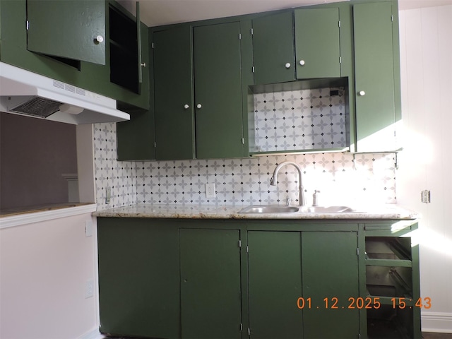 kitchen featuring light stone counters, green cabinetry, sink, and tasteful backsplash