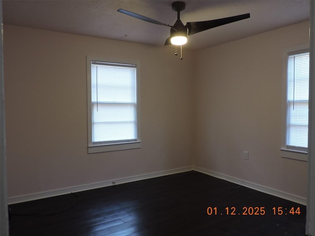 spare room featuring dark wood-type flooring, ceiling fan, and plenty of natural light