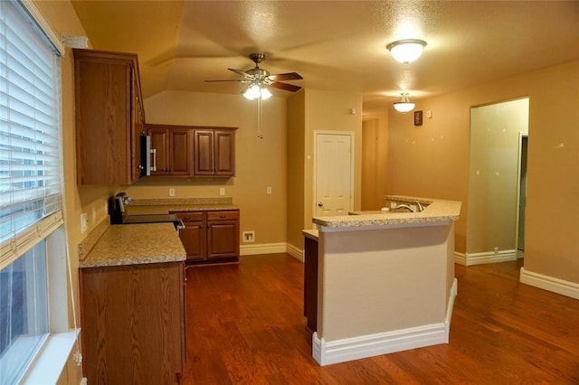 kitchen with stove, dark hardwood / wood-style floors, light stone counters, and ceiling fan