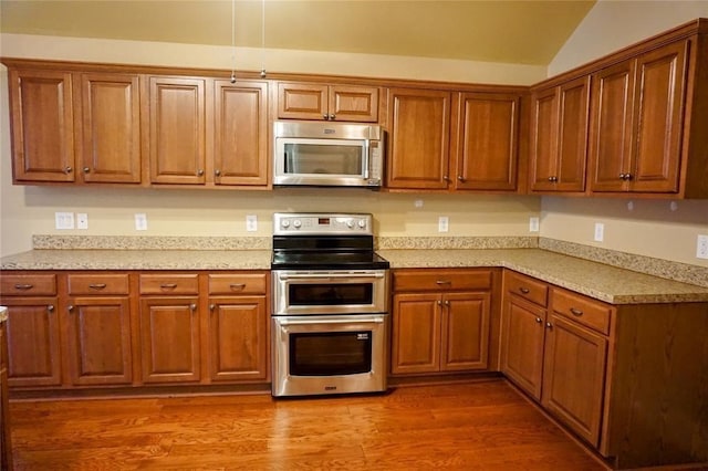 kitchen with vaulted ceiling, wood-type flooring, and appliances with stainless steel finishes