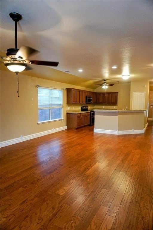 unfurnished living room featuring ceiling fan and dark hardwood / wood-style flooring