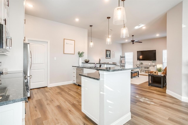 kitchen with pendant lighting, light hardwood / wood-style flooring, stainless steel appliances, white cabinets, and dark stone counters