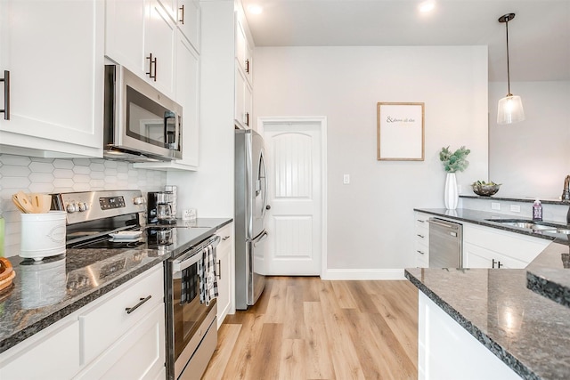 kitchen featuring sink, decorative light fixtures, dark stone countertops, appliances with stainless steel finishes, and white cabinets