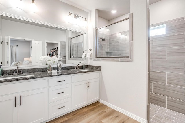 bathroom featuring wood-type flooring, tiled shower, and vanity