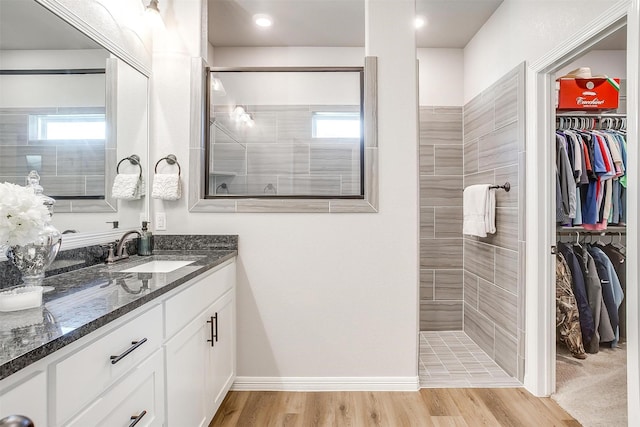 bathroom with tiled shower, vanity, and hardwood / wood-style floors