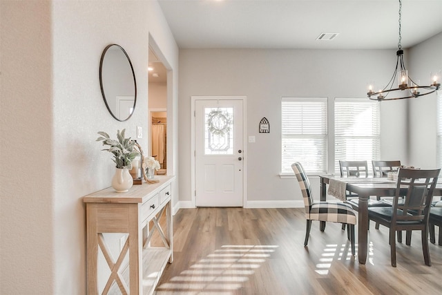 dining space featuring plenty of natural light, light hardwood / wood-style floors, and a notable chandelier