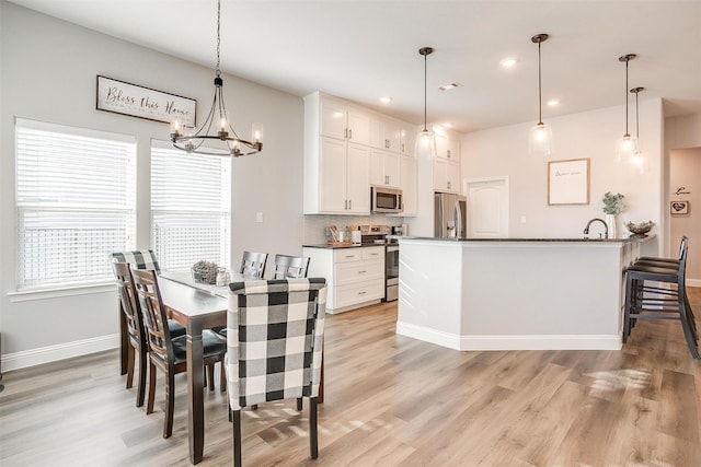 dining space featuring sink, light hardwood / wood-style floors, and a chandelier