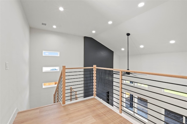 hallway with vaulted ceiling and light wood-type flooring