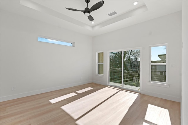 spare room with a raised ceiling, ceiling fan, a towering ceiling, and light hardwood / wood-style floors