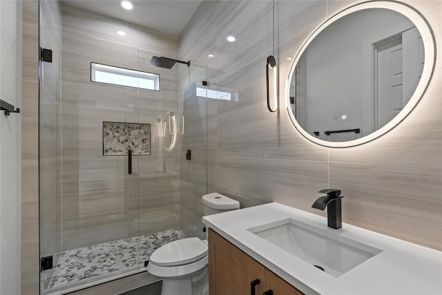 bathroom with walk in shower, vanity, toilet, and tile walls