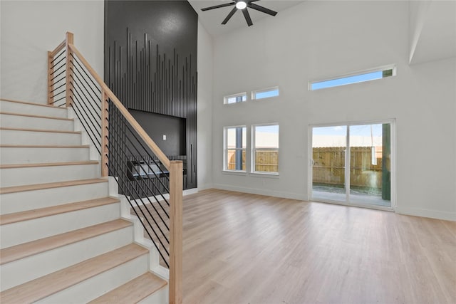 interior space featuring a high ceiling, ceiling fan, and light wood-type flooring