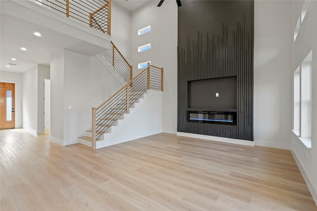 unfurnished living room with a high ceiling and light hardwood / wood-style floors