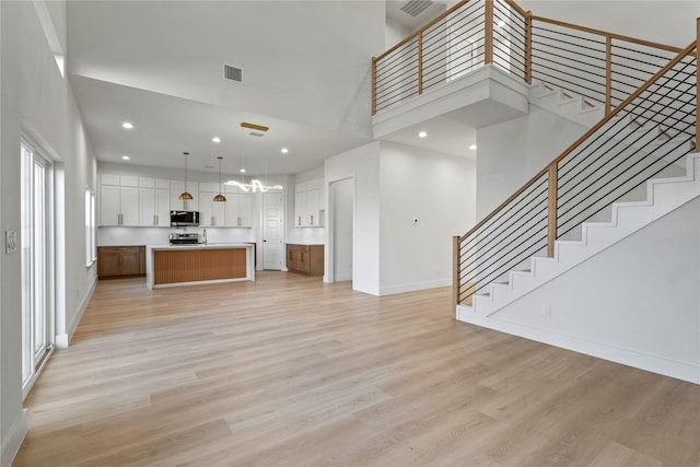 unfurnished living room with a towering ceiling and light hardwood / wood-style flooring