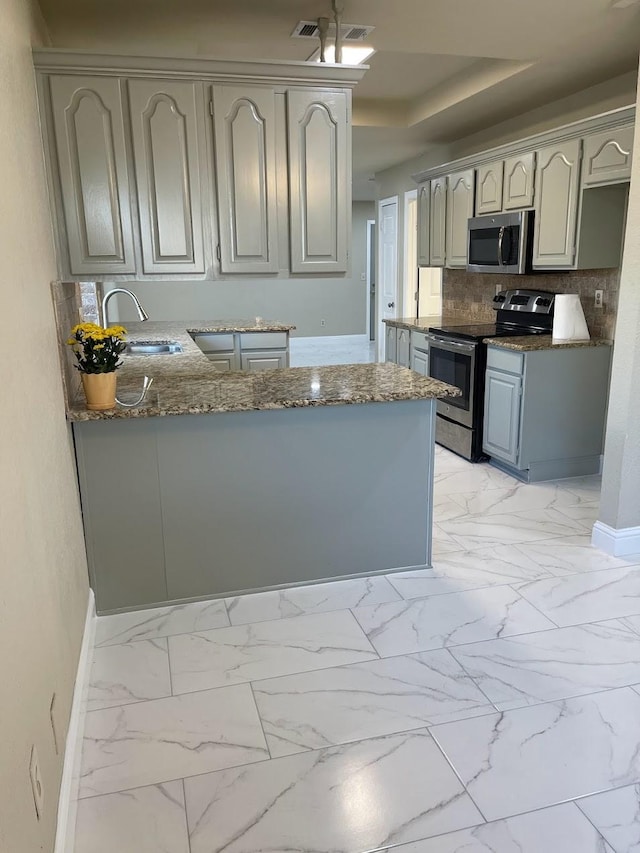 kitchen featuring sink, gray cabinetry, kitchen peninsula, stainless steel appliances, and decorative backsplash