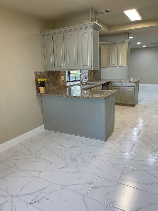 kitchen featuring sink, decorative backsplash, dark stone counters, stainless steel dishwasher, and kitchen peninsula