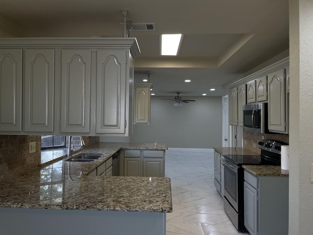 kitchen featuring tasteful backsplash, sink, ceiling fan, kitchen peninsula, and stainless steel appliances