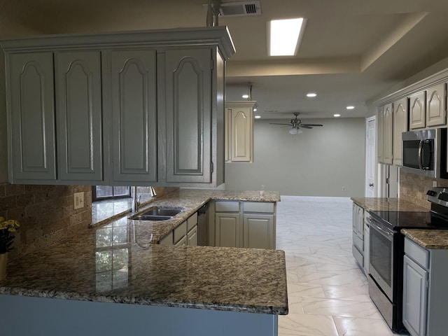 kitchen with gray cabinets, appliances with stainless steel finishes, tasteful backsplash, sink, and kitchen peninsula