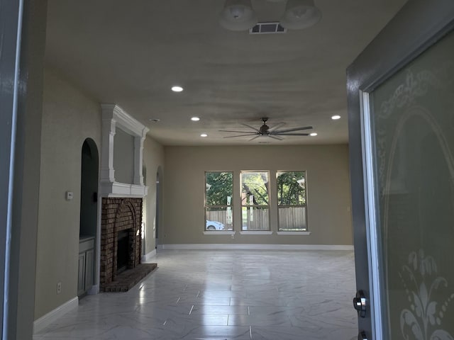 unfurnished living room with ceiling fan and a fireplace