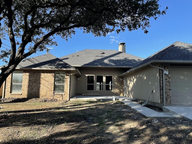 rear view of property featuring a garage and a patio area