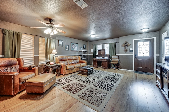 living room featuring hardwood / wood-style flooring, ceiling fan, and a textured ceiling