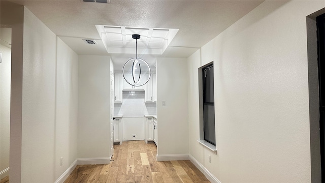 corridor featuring light hardwood / wood-style floors and a tray ceiling