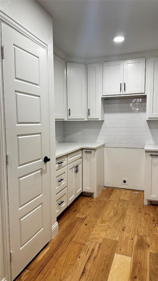 kitchen with tasteful backsplash, light wood-type flooring, and white cabinets