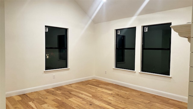 spare room with hardwood / wood-style floors and vaulted ceiling