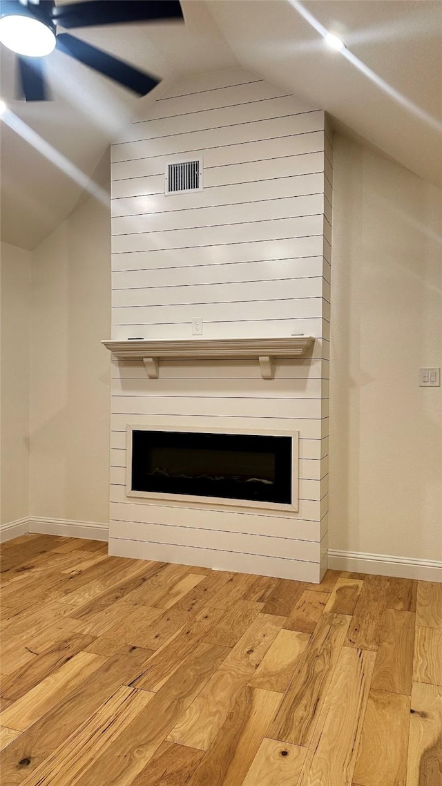 interior details featuring ceiling fan, a large fireplace, and wood-type flooring