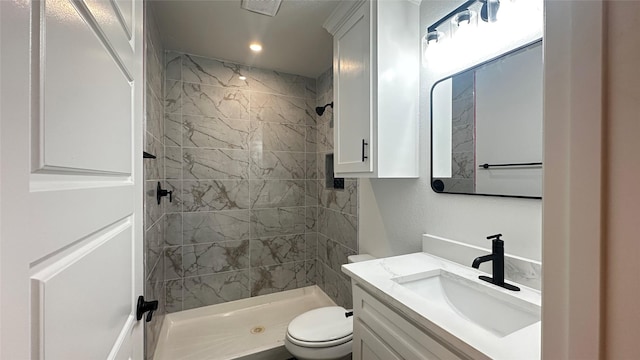 bathroom with vanity, a tile shower, and toilet