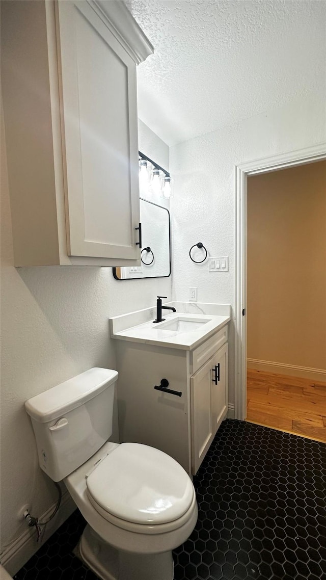 bathroom featuring vanity, toilet, and a textured ceiling