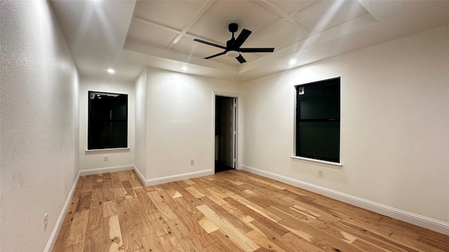 empty room with coffered ceiling, ceiling fan, and light hardwood / wood-style flooring