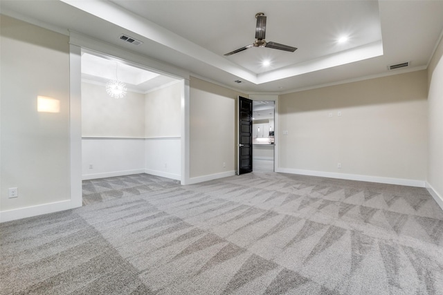 carpeted empty room with ceiling fan with notable chandelier, ornamental molding, and a raised ceiling